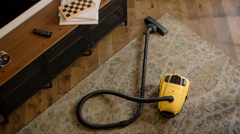 aspirateur jaune à l'arrêt sur une tapis.